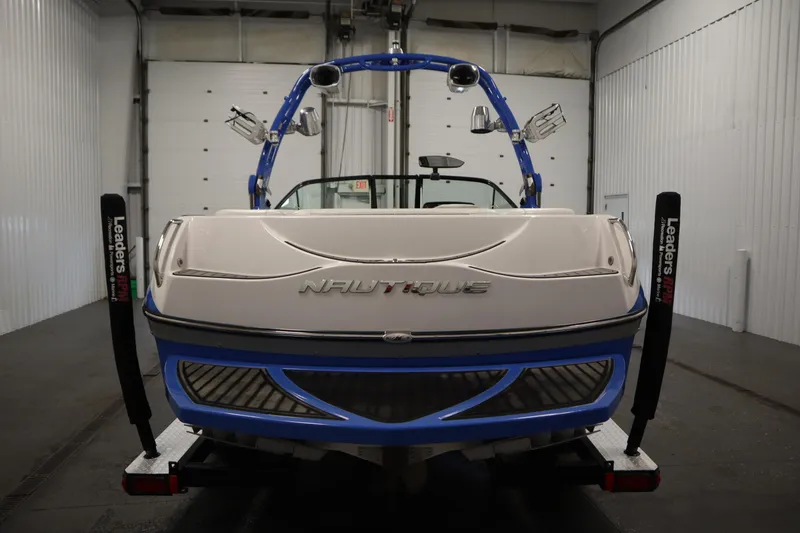 Slide: The Image of 2011 Nautique 210 SUPER AIR boat in a garage, rear view with blue accents. - 6