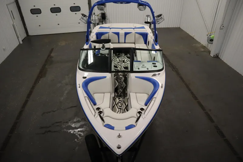 Slide: The Image of 2011 Nautique 210 SUPER AIR boat with blue and white interior in a garage setting. - 9
