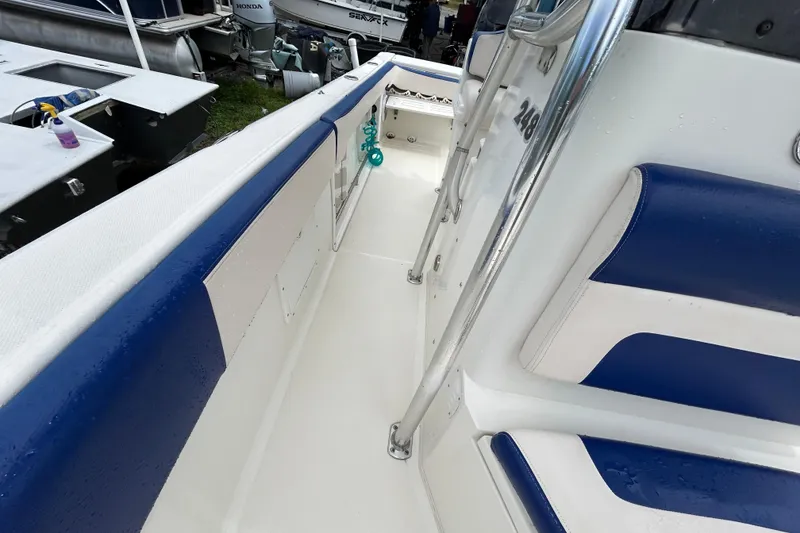 Slide: The Image of 2007 Triton 2486cc boat interior with blue and white seating, metal railings, and clean deck. - 10