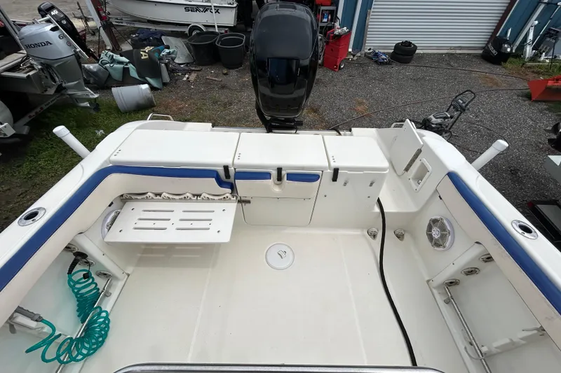 Slide: The Image of 2007 Triton 2486cc boat interior with seating, storage, and motor in a marina setting. - 15