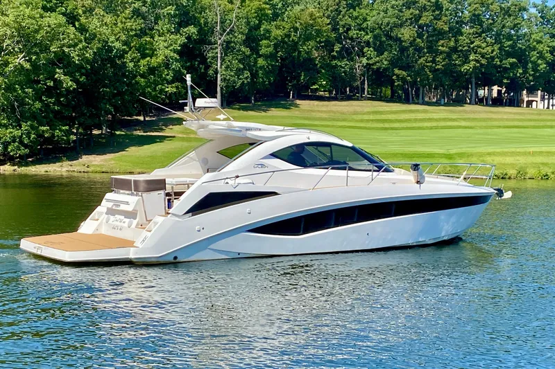 The Image of 2018 Galeon 385 HTS yacht cruising on a serene lake with lush greenery. - 0