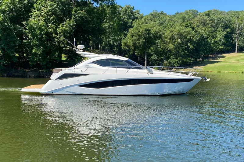 Slide: The Image of 2018 Galeon 385 HTS yacht cruising on a serene lake with lush greenery. - 2