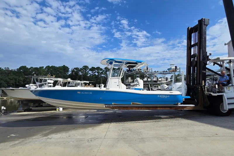 Slide: The Image of 2022 Caymas 28 HB boat in marina, blue hull, elevated on lift, clear sky background. - 6