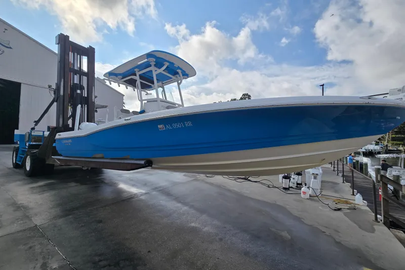 Slide: The Image of 2022 Caymas 28 HB boat on forklift, blue and white, dockside under blue sky. - 7