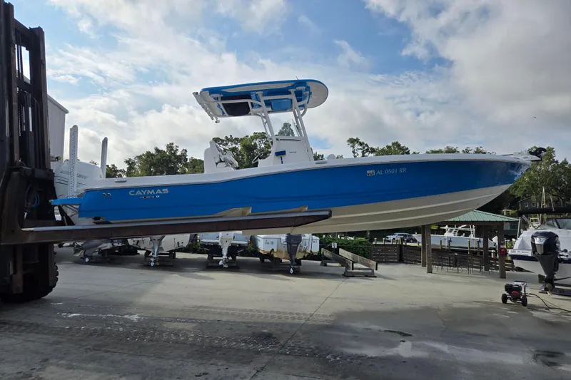 Slide: The Image of 2022 Caymas 28 HB boat in blue, lifted by a forklift at a marina. - 8
