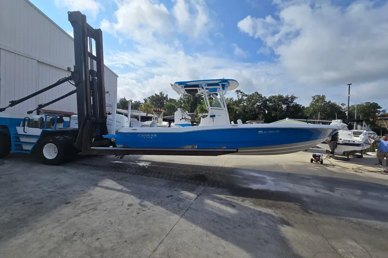 Slide: The Image of 2022 Caymas 28 HB boat in blue, lifted by a forklift at a marina. - 9
