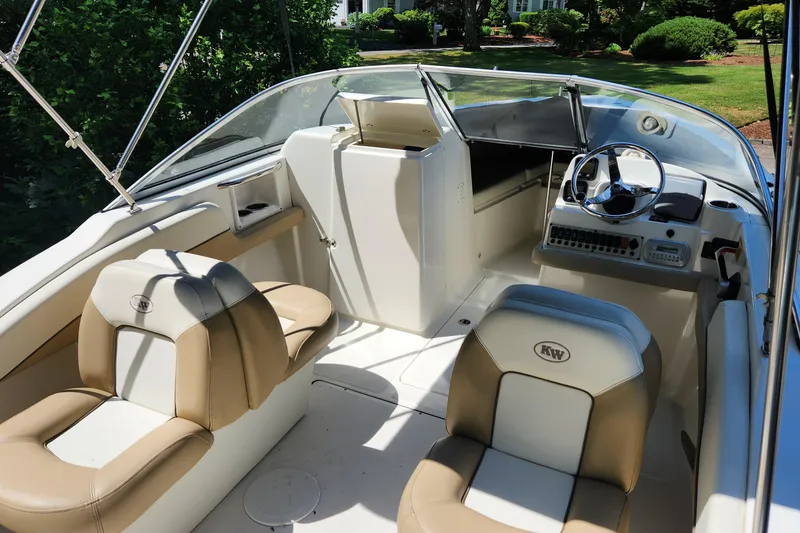 Slide: The Image of 2012 Key West 211 DC boat interior with beige and white seating, steering wheel, and dashboard. - 6