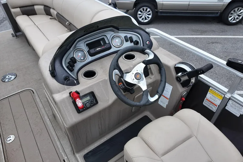 Slide: The Image of 2023 Sun Tracker Party Barge 22 DLX steering console with beige seating and controls. - 7