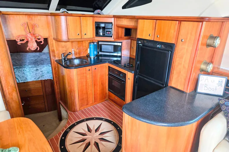 Slide: The Image of 2003 Silverton 392 Motor Yacht interior with kitchen, wood cabinetry, and nautical decor. - 5