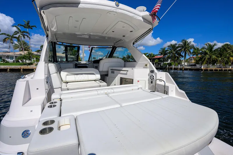 Slide: The Image of 2020 Regal 35 Sport Coupe yacht with luxurious seating, docked by palm trees and waterfront homes. - 1