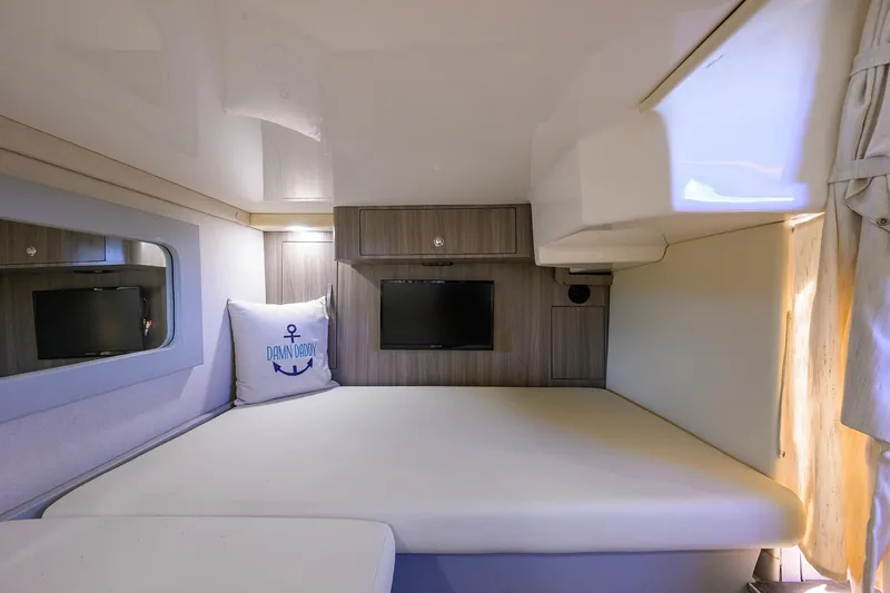 Slide: The Image of 2020 Regal 35 Sport Coupe cabin interior with bed, TV, and nautical-themed pillow. - 27