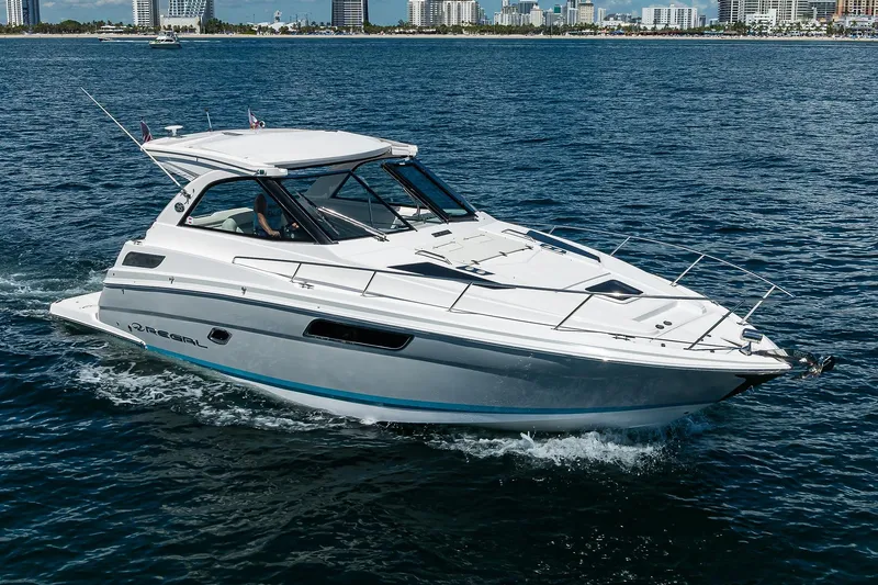 Slide: The Image of 2020 Regal 35 Sport Coupe cruising on open water with city skyline in background. - 38