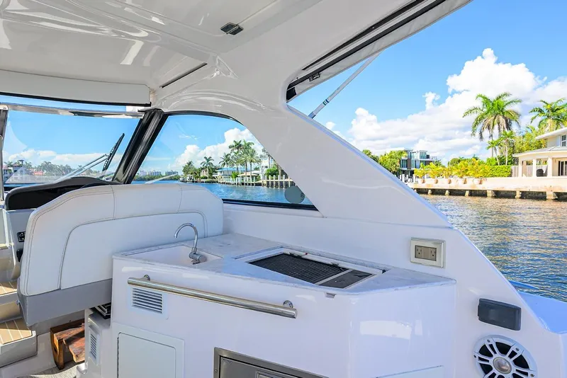 Slide: The Image of 2020 Regal 35 Sport Coupe interior with kitchenette, overlooking scenic waterfront and palm trees. - 4
