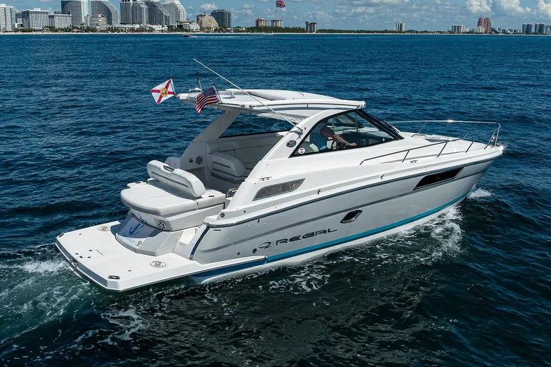 Slide: The Image of 2020 Regal 35 Sport Coupe cruising on open water with city skyline in background. - 43