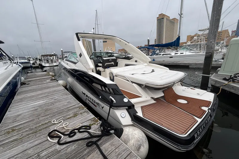 Slide: The Image of 2014 Monterey 328 Super Sport boat docked at a marina, featuring sleek design and wooden deck. - 7