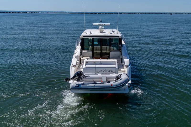 Slide: The Image of 2020 Tiara Yachts C44 Coupe on open water, rear view with inflatable boat. - 17