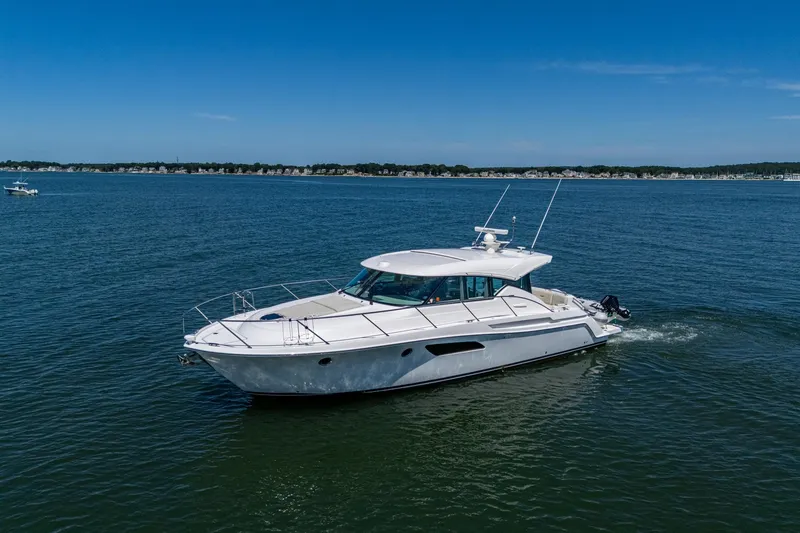 Slide: The Image of 2020 Tiara Yachts C44 Coupe cruising on open water under clear blue skies. - 2