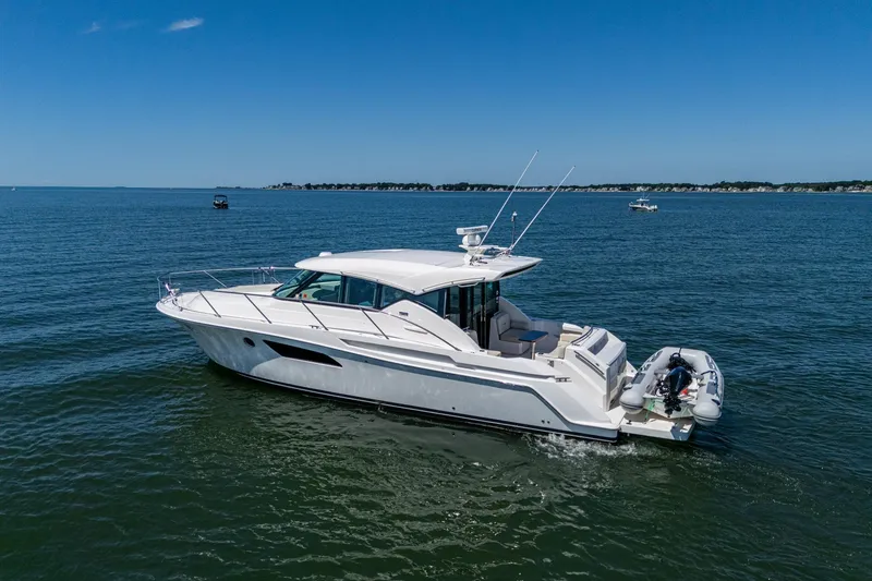 Slide: The Image of 2020 Tiara Yachts C44 Coupe cruising on open water under clear blue skies. - 20