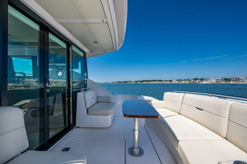 Slide: The Image of 2020 Tiara Yachts C44 Coupe deck with seating, overlooking serene waters and shoreline. - 37
