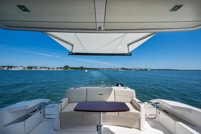 Slide: The Image of 2020 Tiara Yachts C44 Coupe, rear deck view, overlooking serene waters and distant shoreline. - 40