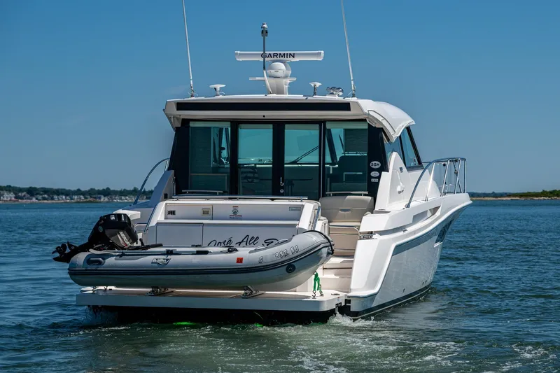 Slide: The Image of 2020 Tiara Yachts C44 Coupe cruising on open water with inflatable boat attached. - 64