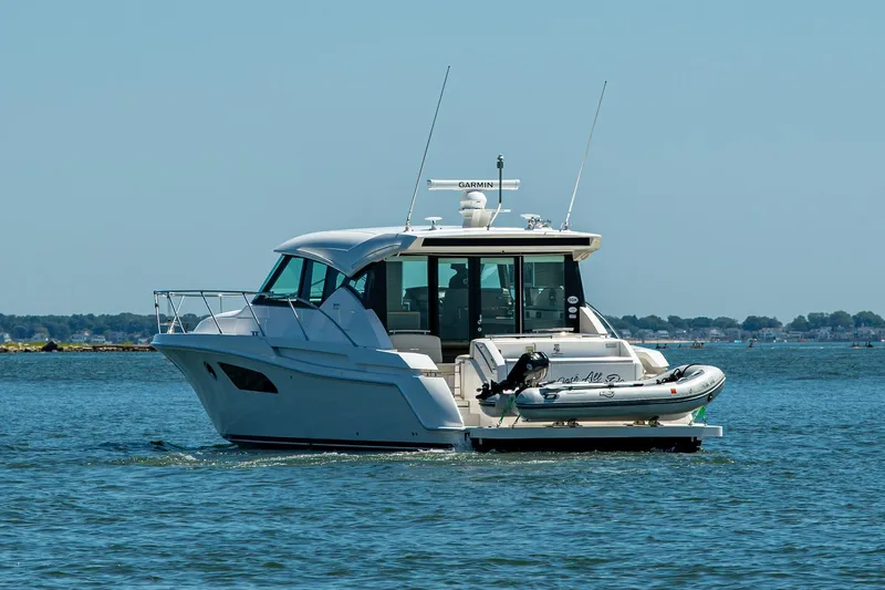 Slide: The Image of 2020 Tiara Yachts C44 Coupe cruising on open water with inflatable boat attached. - 66