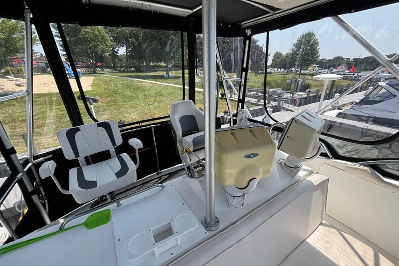 Slide: The Image of 1998 Bertram 33 Convertible Sport Fisherman cockpit with seating and controls, docked near grassy area. - 11