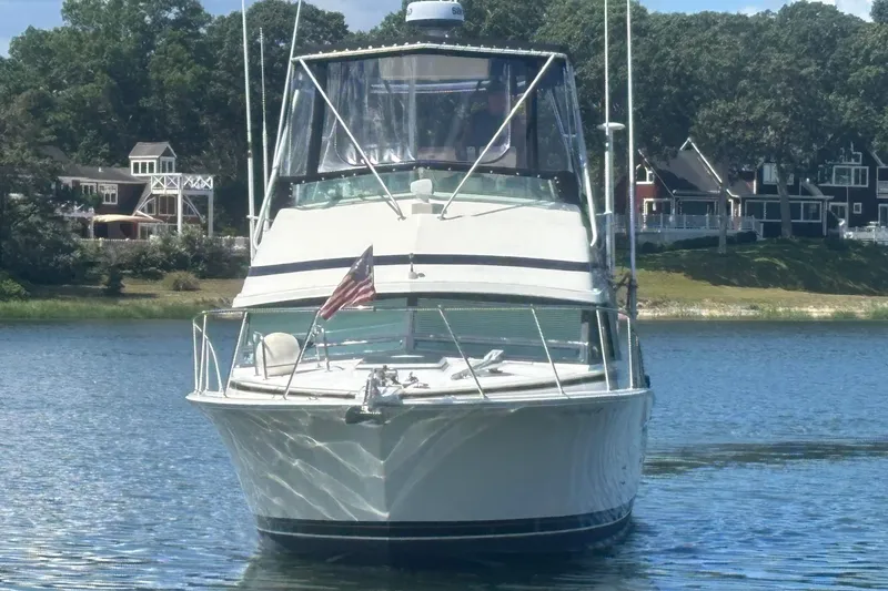 Slide: The Image of 1998 Bertram 33 Convertible Sport Fisherman boat on calm water, with scenic background. - 3