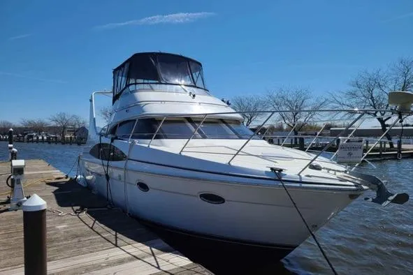 Slide: The Image of 2002 Carver 410 Sport Sedan yacht docked at a marina under clear blue skies. - 1