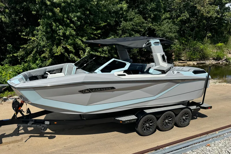 Slide: The Image of 2026 Nautique Super Air Nautique G23 Paragon boat on trailer, surrounded by greenery. - 1
