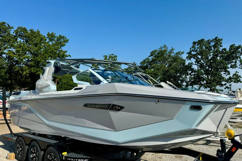 Slide: The Image of 2026 Nautique Super Air Nautique G23 Paragon boat on trailer, surrounded by trees. - 4