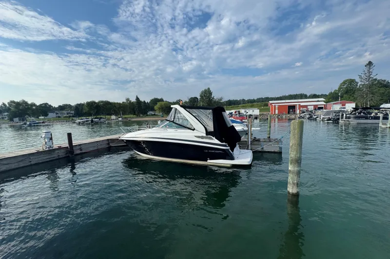 The Image of 2012 Regal 28 Express boat docked at a marina under a partly cloudy sky. - 0