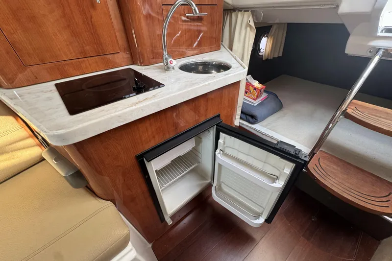 Slide: The Image of 2012 Regal 28 Express cabin with kitchenette, open fridge, and cozy sleeping area. - 19