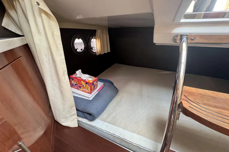 Slide: The Image of 2012 Regal 28 Express cabin interior with bed, portholes, and wooden accents. - 25