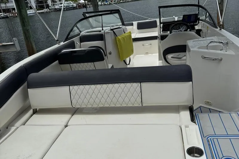 Slide: The Image of 2020 Bayliner DX2200 boat interior with seating, steering wheel, and sink, docked at marina. - 11