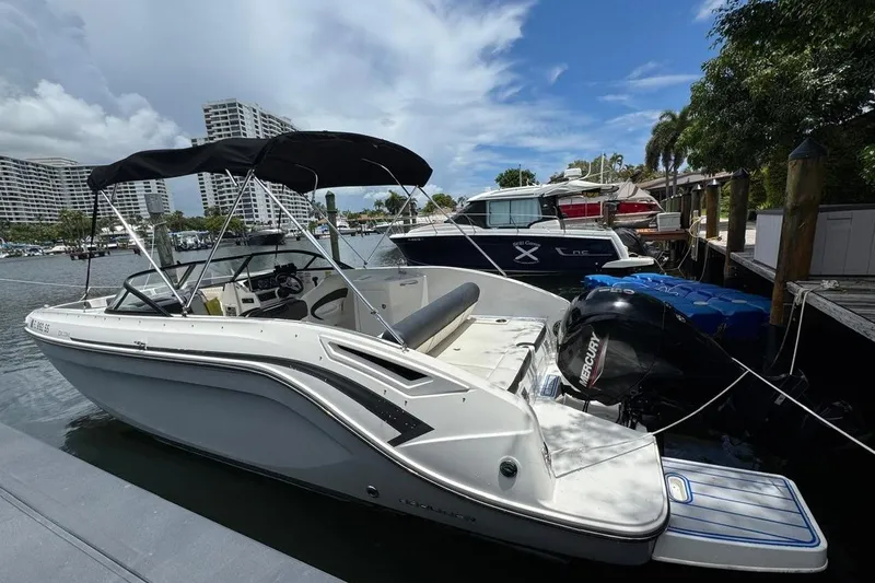 Slide: The Image of 2020 Bayliner DX2200 boat docked at marina with scenic waterfront view. - 3