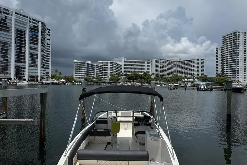 Slide: The Image of Bayliner DX2200 boat docked in marina with modern buildings and cloudy sky. - 4
