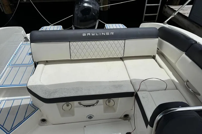 Slide: The Image of 2020 Bayliner DX2200 boat seating area with cushioned bench and storage compartments. - 9