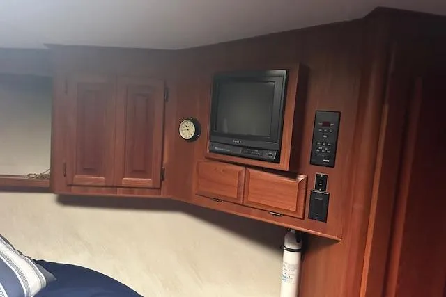 Slide: The Image of 1988 Viking 45 Convertible cabin interior with TV, clock, and wooden cabinets. - 21