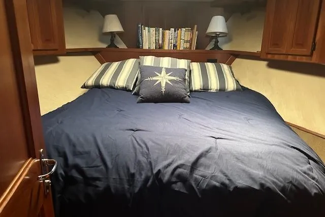 Slide: The Image of Cozy bedroom in 1988 Viking 45 Convertible yacht with nautical-themed bedding and bookshelves. - 22