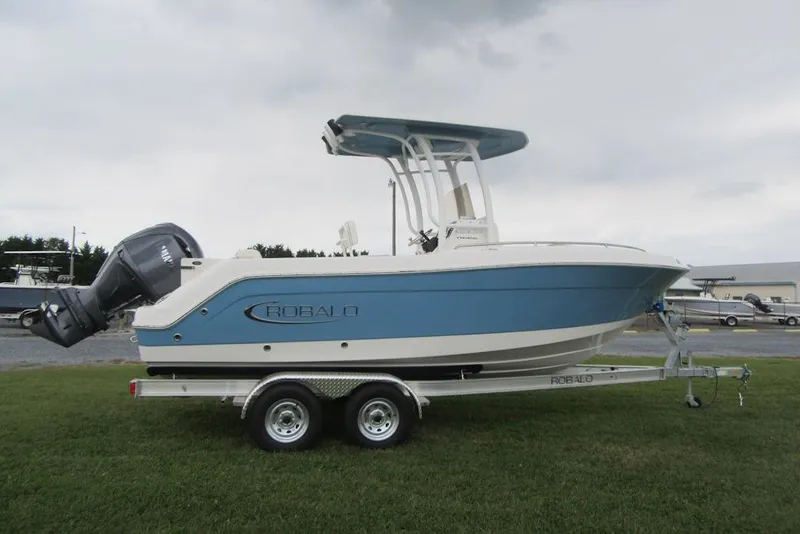 Slide: The Image of 2026 Robalo R222 Center Console boat on trailer, parked on grass under cloudy sky. - 2