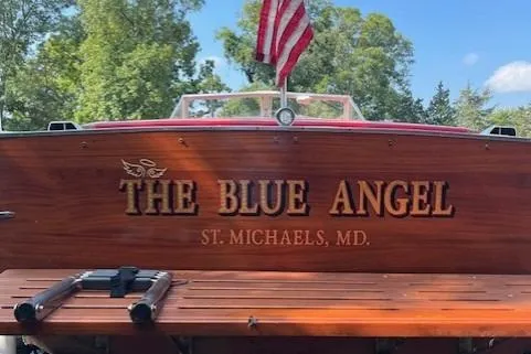 Slide: The Image of 1963 Chris-Craft Sea Skiff boat with red flag, docked near trees under clear blue sky. - 5