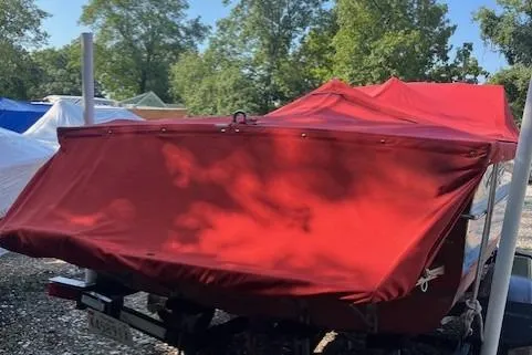 Slide: The Image of 1963 Chris-Craft Sea Skiff boat on trailer, blue and white hull, red flag, surrounded by trees. - 2