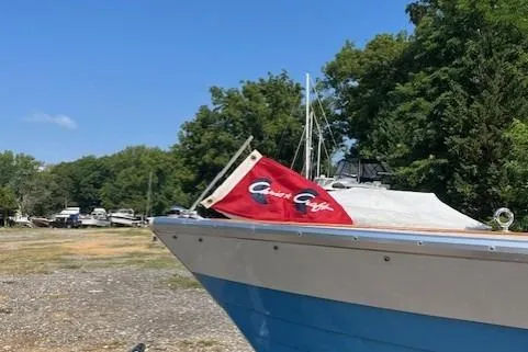 Slide: The Image of 1963 Chris-Craft Sea Skiff with red cover on trailer, surrounded by trees. - 3