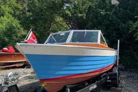 Slide: The Image of 1963 Chris-Craft Sea Skiff with red cover, parked outdoors among trees. - 4