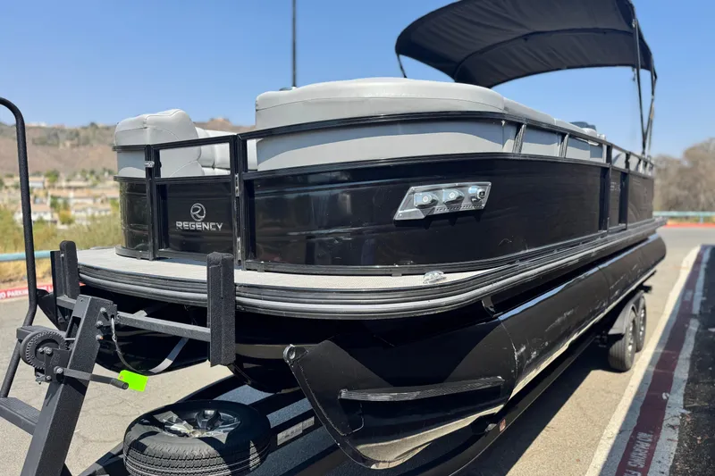 Slide: The Image of 2023 Regency 250 LE3 pontoon boat on trailer, featuring sleek black design and canopy. - 3