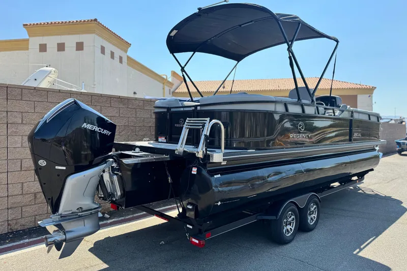 Slide: The Image of 2023 Regency 250 LE3 pontoon boat with Mercury outboard engine, parked on a trailer. - 6