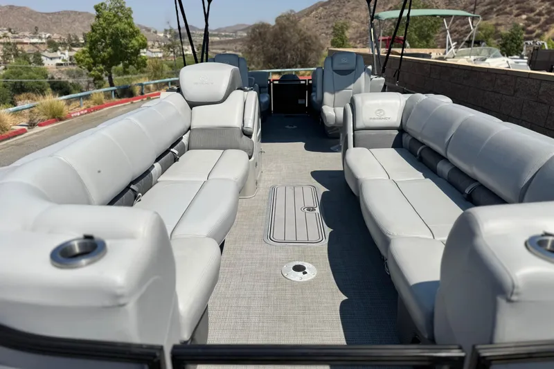 Slide: The Image of 2023 Regency 250 LE3 pontoon boat with spacious gray seating and scenic background. - 8