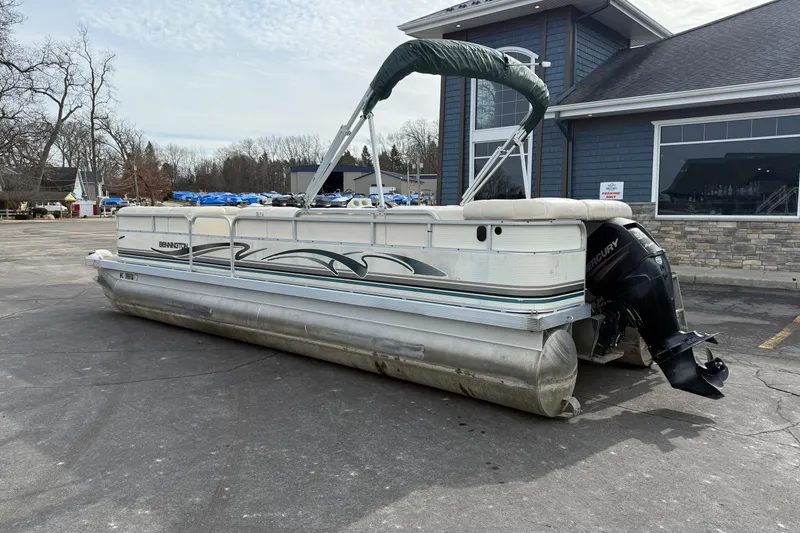 Slide: The Image of 2001 Bennington 2550 RL pontoon boat with Mercury outboard motor, parked near a building. - 4
