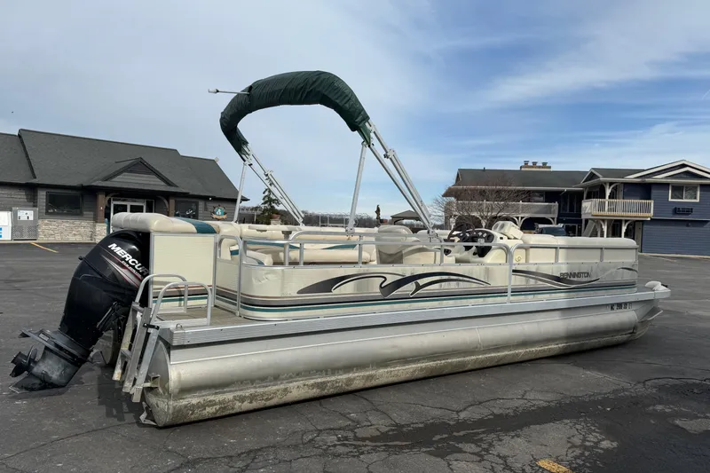 Slide: The Image of 2001 Bennington 2550 RL pontoon boat with Mercury outboard motor, parked near buildings. - 7